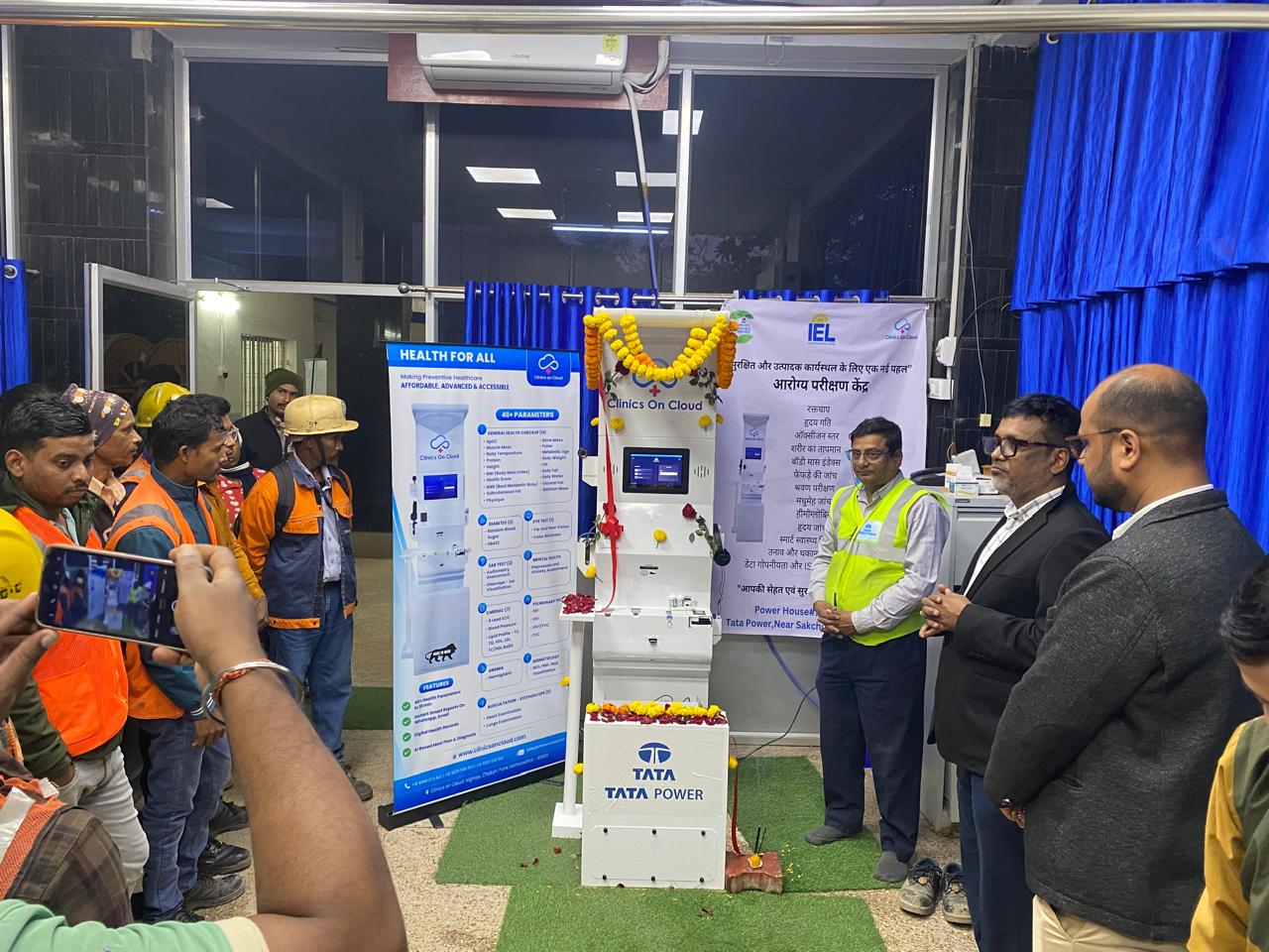 Garland Clinics on Cloud health kiosk unveiled at a Tata Power site, with workers and officials gathered around it.