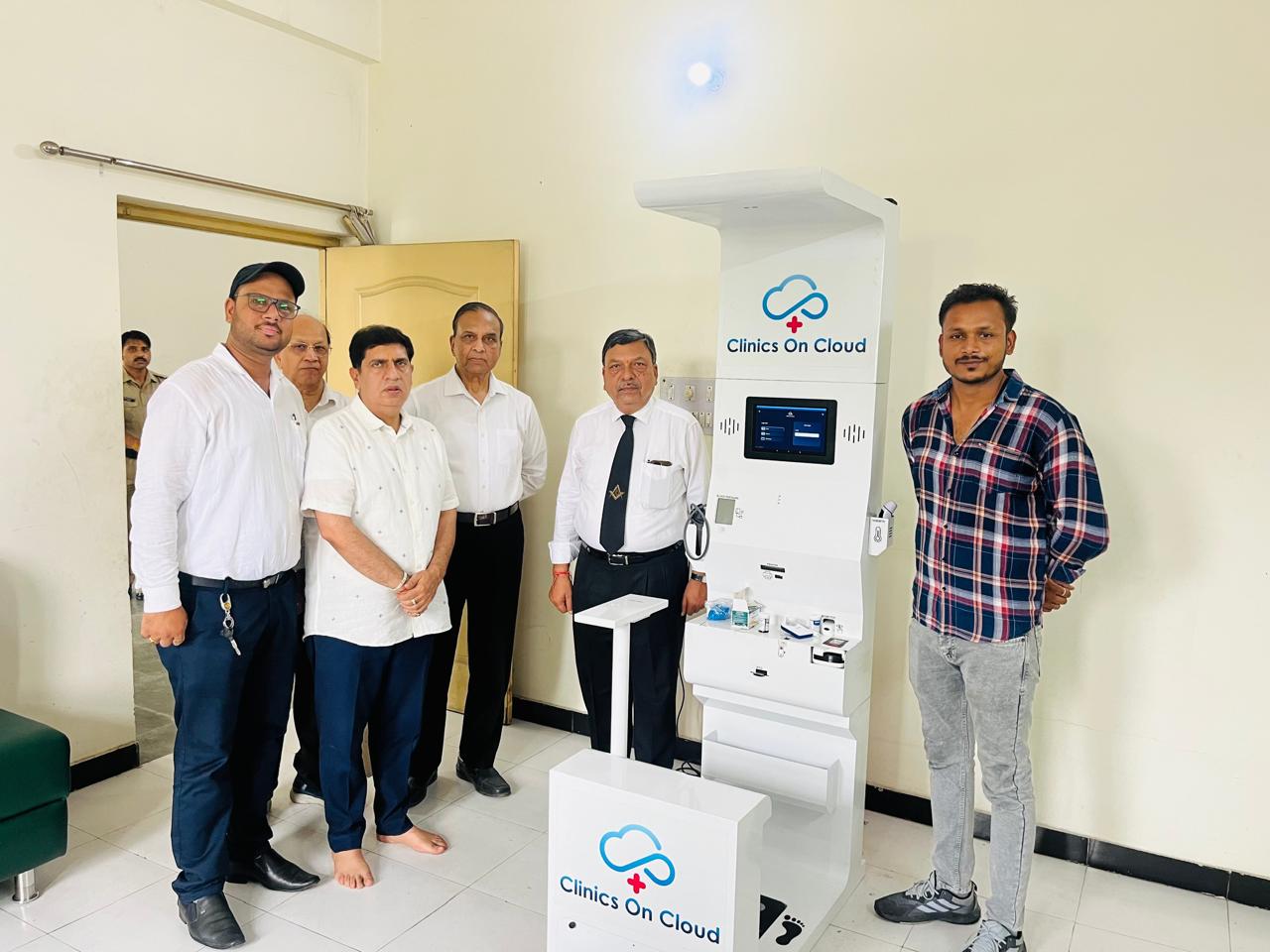 Group of men standing beside a Clinics On Cloud health kiosk in an indoor room